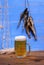 Mug of beer on blue background with dried rudd fish