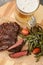 Mug with beer, delicious fried steak and asparagus on wooden table, above view