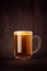 Mug beer glass with golden sparkling lager on dark wood board, vertical. Template for advertising, design, branding identity, rest