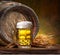 Mug of chilled beer, wheat ears and wooden beer cask on the wooden table