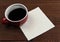A mug of coffee with a blank napkin on a rustic wood table. Room for your copy or doodle