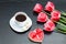Mug of coffee and heartshaped gingerbread, five pink tulips. Black background.