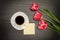 Mug of coffee and marshmallows, clean postcard, three pink tulips. Black background. top view