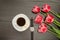 Mug with coffee, watch, pink tulips. Black table. Top view