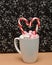 A mug filled with small marshmallows and candy cane
