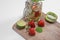 Mug of fruit water with strawberries, mint, lemon, kiwi and lime stand on a wooden stand next to fresh strawberries, lime and mint