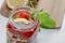 Mug of fruit water with strawberries, mint and lemon, stand on a wooden stand next to fresh strawberries, mint leaves and sliced