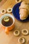 Mug full of black tea with lemon, croissant on plate and small bagels