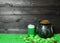 Mug of green beer and cast iron pot with four-petal lucky shamrock leaf, full of leprechaun gold treasure, shamrock leaves and