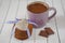Mug with hot cocoa topped gingerbread cookies, metallic heart souvenir and chocolate chips on a white wooden tabl