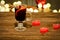 Mug of mulled wine with spices, candles in the shape of a heart on a wooden table. Garland of lanterns in the background