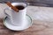 Mug on saucer with tea and cinnamon on wooden background