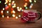 Mug in a scarf on a wooden background. Christmas and New Year garlands on a wooden background. Winter holidays, new year mood.