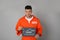Mug shot of prisoner in orange jumpsuit with board on grey background, front view