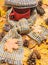 Mug of tea covered with hat and surrounded by scarf autumnal background with fallen maple leaves and fir cones. Warming