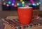 Mug with tea, on wooden table, under colored defocused background,