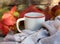 Mug with warm tea on wooden bench on fallen autumn leaves in the forest, outdoor weekend, fall camping.