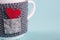 A mug wrapped in a warm cover - an envelope with a message of love, a Valentine`s day, a concept of congratulations. Macro