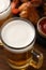 Mugs with beer and delicious baked chicken wings on wooden table, closeup