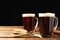 Mugs of delicious kvass, spikes and bread on table against black background. Space for text