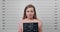 Mugshot of young arrested woman holding sign for photo in police department. Crop view of adult female criminal posing