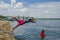 Muisne, Ecuador - March 16, 2016: Kids diving and swimming in pacific ocean from stone surface with clothes on