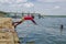 Muisne, Ecuador - March 16, 2016: Kids diving and swimming in pacific ocean from stone surface with clothes on