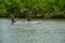 Muisne, Ecuador - March 16, 2016: Man and woman sitting inside small canoe paddling alongside shoreline, heavy green