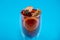 Mulled wine on blue background. Alcohol punch in double glass cup. Drink with orange, anise star, cinnamon and apple.