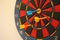 Multi color dart board with darts stuck in it