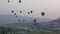 Multi-colored balloons fly over rocks.