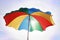 Multi-colored beach umbrella against the background of a light s