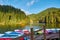 Multi-colored boats at the pier on Lake Lacu Rosu, Romania. Autumn landscape of mountain lake, forest