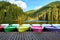 Multi-colored boats at the pier on Lake Lacu Rosu, Romania. Autumn landscape of mountain lake, forest and mountains