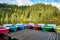 Multi-colored boats at the pier on Lake Lacu Rosu, Romania. Autumn landscape of mountain lake, forest and mountains