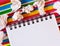 On a multi-colored bright striped background near the crumpled white papers lies a white blank notebook on springs. Close-up top