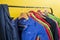 Multi-colored children`s workwear for creative work hangs on hangers, against the backdrop of a bright yellow wall, in a kids clu