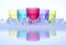 Multi colored of cool water glasses with cube ices and reflection on a glass table, on white background