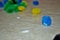 Multi colored cotton pompoms, glue, glue sticks, construction paper, and scissors covering a linoleum floor during arts and crafts