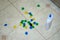 Multi colored cotton pompoms, glue, glue sticks, construction paper, and scissors covering a linoleum floor during arts and crafts