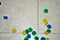 Multi colored cotton pompoms, glue, glue sticks, construction paper, and scissors covering a linoleum floor during arts and crafts