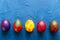 Multi-colored decorative colourful eggs on a blue background with copy space. Top view