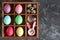 Multi-colored Easter eggs and a rabbit-shaped clock in wooden cells on a concrete background. Top view