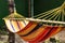 A multi-colored fabric hammock hangs in the trees, in the rays of the sun, in the open air