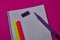 Multi colored felt tip pens and binder notepad at magenta background with copy space