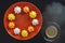 Multi-colored figured cookies on a round orange plate and a cup of hot coffee on a black background