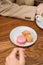 Multi-colored french macaron cookies with different fillings on plates, a female hand holds a bitten macaroon. Close-up shot