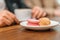 Multi-colored french macaron cookies with different fillings on plates, a female hand holds a bitten macaroon. Close-up shot