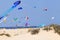 Multi colored kites over sandy dunes, beach .