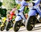 Multi-colored mopeds parked on the street surrounded by green trees